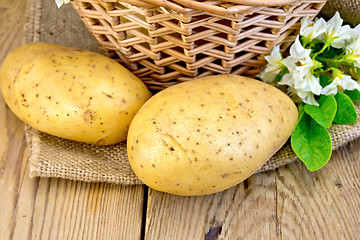 Image showing Potatoes yellow with flower and basket on sackcloth