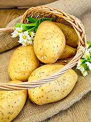 Image showing Potatoes yellow with flower in basket on sacking