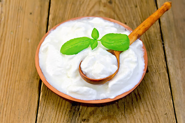 Image showing Yogurt in clay bowl with spoon on board