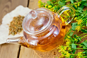 Image showing Tea with fresh and dry tutsan in glass teapo on board