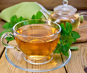 Image showing Tea with mint and napkin on wooden board