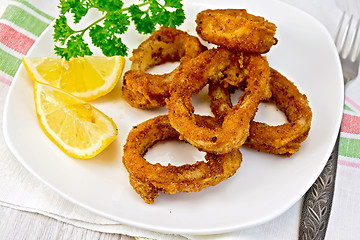 Image showing Calamari fried with lemon and fork on plate