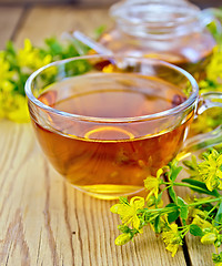 Image showing Tea from tutsan in glass cup and teapot on board