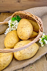 Image showing Potatoes yellow in basket with flower on sackcloth and board