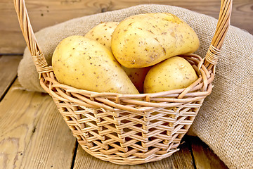 Image showing Potatoes yellow in basket with burlap on board