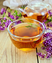 Image showing Tea of oregano in glass cup on board with teapot