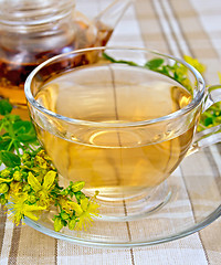 Image showing Tea from tutsan in glass cup and teapot on tablecloth