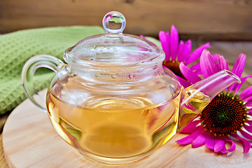 Image showing Tea from Echinacea in glass teapot on board with cloth