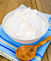 Image showing Yogurt in white bowl with spoon on board