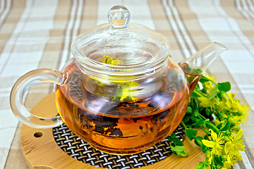 Image showing Herbal tea from tutsan in glass teapot on linen tablecloth