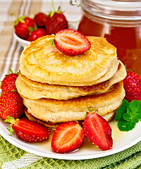 Image showing Flapjacks with strawberries and honey on tablecloth