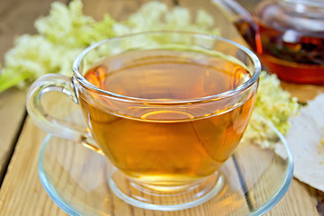 Image showing Tea from meadowsweet in glass cup and teapot on board