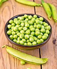 Image showing Green peas in brown bowl on board