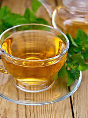 Image showing Tea with mint in cup and teapot on wooden board