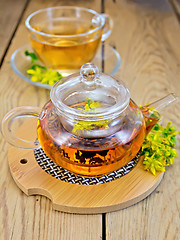 Image showing Herbal tea from tutsan in glass teapot on stand with cup