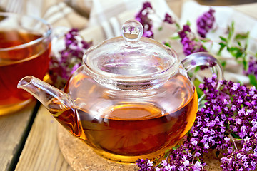 Image showing Tea of oregano in glass teapot on board with napkin