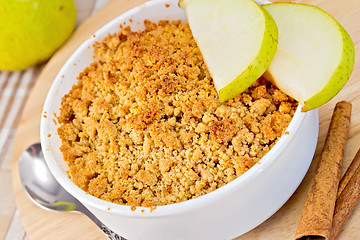 Image showing Crumble with pears in bowl on linen tablecloth and board