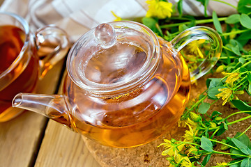 Image showing Herbal tea from tutsan in glass teapot with cup on board