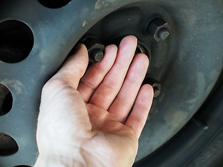 Image showing Person checking rusty nuts on a steel rim of a vehicle