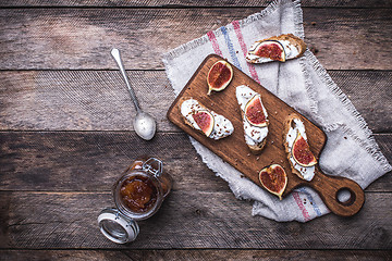 Image showing rustic style Bruschetta with jam and Sliced figs on chopping boa