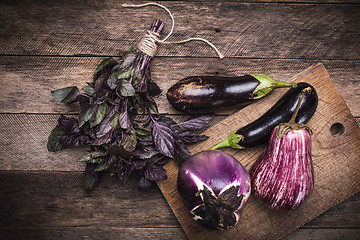 Image showing Aubergines and basil on chopping board in rustic style