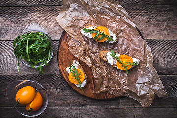 Image showing Bruschetta with tomatoes and arugula on board in rustic style