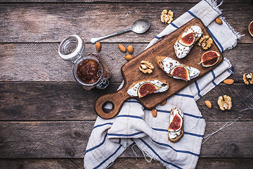 Image showing Bruschetta with figs and nuts on board in rustic style