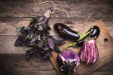 Image showing Rustic style Aubergines and basil on chopping board 