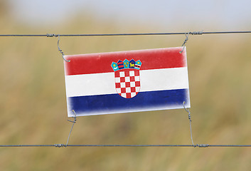 Image showing Border fence - Old plastic sign with a flag