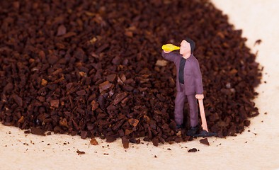 Image showing Miniature worker working on grinded coffee