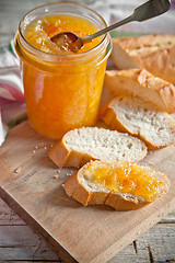 Image showing orange jam in a glass jar and bread