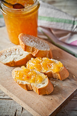 Image showing orange jam in a glass jar and bread