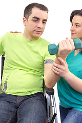 Image showing Physical therapist works with patient in lifting hands weights.