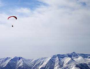 Image showing Paraglider silhouette of mountains in sunlight sky