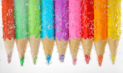 Image showing Colorful pencils in water with bubbles, isolated on white