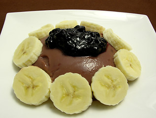 Image showing Chocolate pudding arranged with banana slices and blueberry jam on a white plate