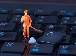 Image showing Miniature worker with broom working on keyboard