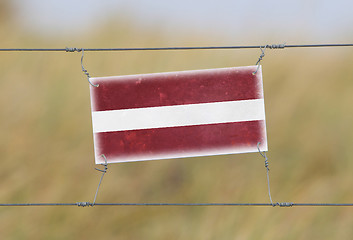 Image showing Border fence - Old plastic sign with a flag