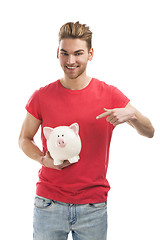 Image showing Handsome young man holding a piggy bank