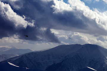 Image showing Helicopter in winter mountains and cloudy sky in evening