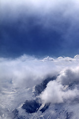 Image showing Snowy mountains in clouds and sunlight sky