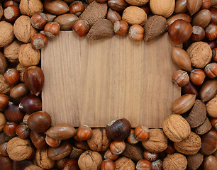Image showing Mixed nuts frame a wooden background