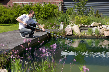 Image showing man cleanse his garden pond, mann reinigt seinen gartenteich