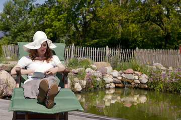 Image showing woman enjoys garden pond lies, frau geniesst gartenliege teich