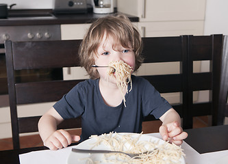 Image showing Boy has mouth full of pasta in kitchen