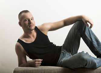 Image showing man in muscle shirt lying on a sofa