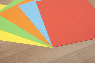 Image showing colored paper on wooden background