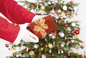 Image showing Santa Claus with gift front of tree