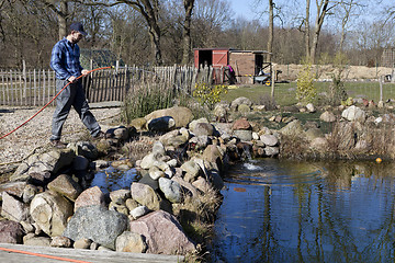 Image showing man with hose on the garden pond