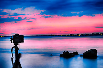 Image showing Dslr camera shooting on a beutiful seascape with blue red sky su